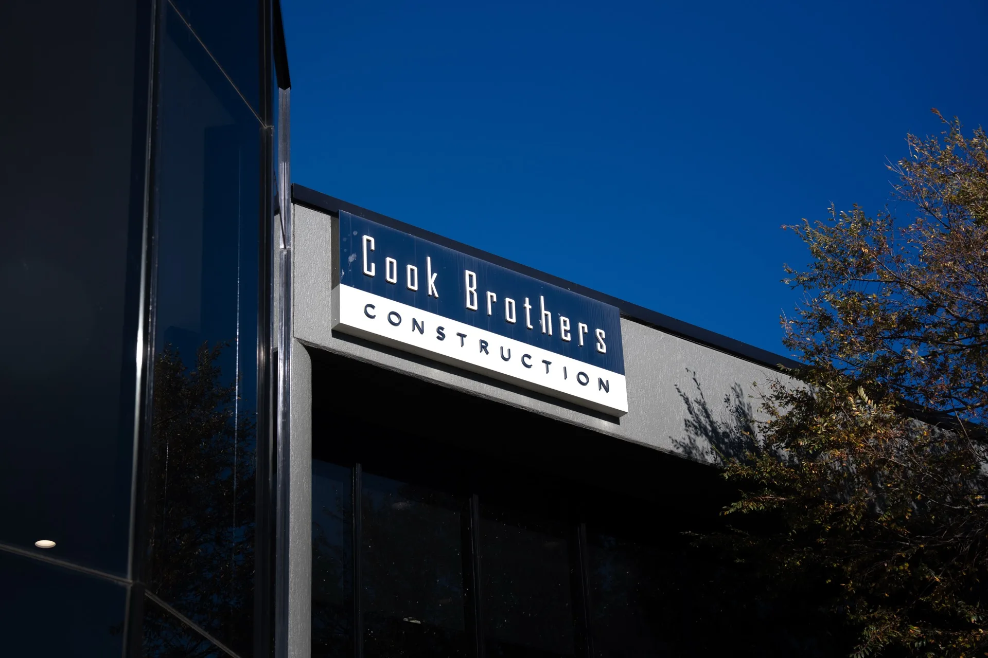 Cook Brothers Construction illuminated facade signage at night by Universal Sign Co