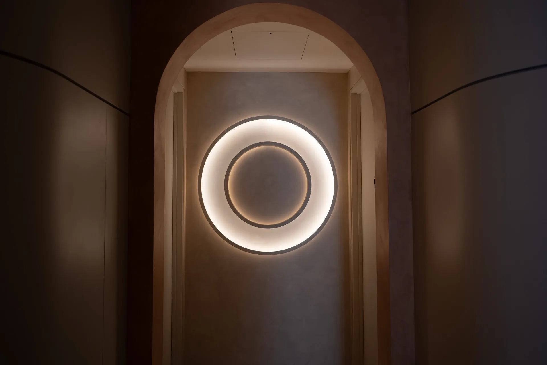 Illuminated O-Studio logo glowing in an arched alcove, painted to match the surrounding wall, by Universal Sign Co