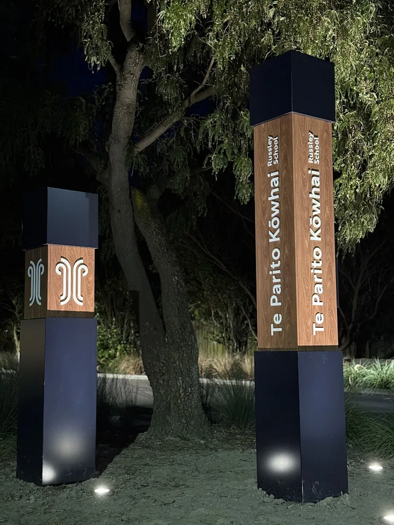 Te Parito Kōwhai — spot lighting washing up the timber-textured cladding